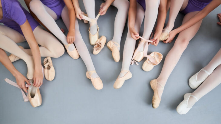 Little ballerinas putting on slippers.